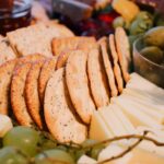 Close-up of a gourmet cheese and cracker platter with fresh grapes and olives, perfect for entertaining.