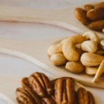 Close-up of assorted nuts in wooden spoons showcasing a healthy and organic snack option.