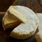 Delicious Camembert cheese wheel and slice showing creamy texture.